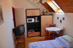 sypialnia z łóżkiem, telewizorem i stołem w obiekcie Orchidea Apartman w Hévízie