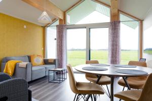 a living room with a table and chairs and a couch at Eco Holiday Home - Airco & Panoramisch uitzicht - Achterhoek in Almen