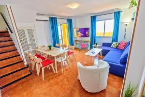 a living room with a blue couch and a table and chairs at Beachfront Duplex 1ª línea & Terraces Oceanfront in El Puerto de Santa María