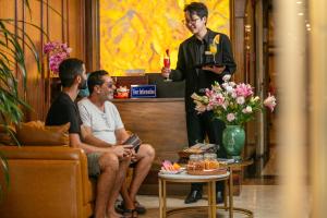 een man die een glas wijn vasthoudt voor twee mannen bij The West Hotel & Spa in Hanoi