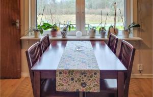 a dining room table with two chairs and plants at Lovely Home In Hishult With Wifi in Drakabygget