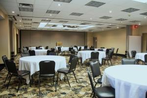 una sala de conferencias con mesas y sillas blancas en Lamplighter Inn & Suites Pittsburg, en Pittsburg