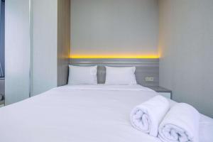 a bedroom with a white bed with towels on it at Restful and Homey 2BR at Transpark Cibubur Apartment By Travelio in Depok +9 photos