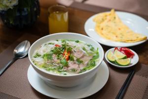 een kom soep op een tafel met een bord eten bij The West Hotel & Spa in Hanoi +70 foto's