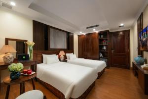 a bedroom with two beds and a desk and a tv at The West Hotel & Spa in Hanoi +69 photos