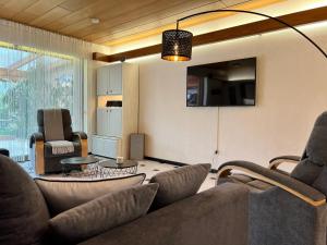 a living room with a couch and chairs and a tv at Barrierefreies Ferienhaus mit Garten bei Köln in Hürth
