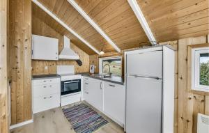 a kitchen with white cabinets and a refrigerator at Holiday Home Sdr Klitvej Hvide Sande in Havrvig +11 photos