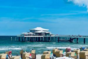 a beach with chairs and a pier in the ocean at Country Hotel Timmendorfer Strand in Timmendorfer Strand