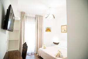 una camera da letto bianca con un letto e una televisione di B&B La Melagrana a Paestum