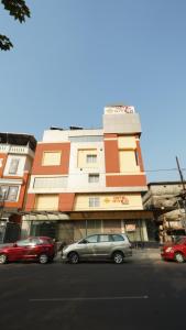 科泽科德Hotel Hive Inn - Kozhikode的街道前有车辆停放的建筑物
