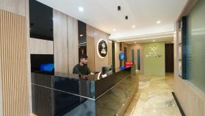 科泽科德Hotel Hive Inn - Kozhikode的坐在台上手提电脑的人