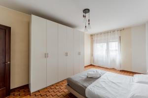 a bedroom with a bed with white cabinets and a window at Miranda - Apartament in Mestre with Balcony! in Marghera
