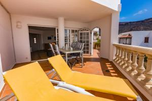 a patio with yellow chairs and a table on a balcony at Apartment Chateau Morro 7 in Morro del Jable