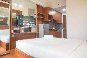 a bedroom with a white bed and a tv at Relaxing and Homey Studio Transpark Cibubur Apartment By Travelio in Depok
