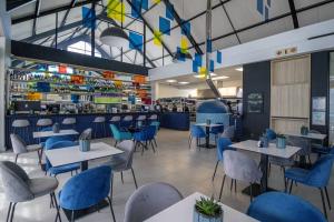 a restaurant with white tables and blue chairs at Bella Mare 13 on Boardwalk in Gqeberha