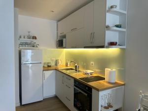 a kitchen with white cabinets and a white refrigerator at Sunset Studio Apartment in Lezhë