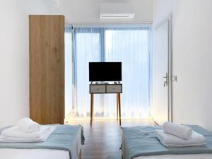 a bedroom with two beds and a television on a table at Saint 40 Suites Premium Flat in Sarandë