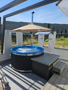 a hot tub with an umbrella and a bench at TinyApartament in Skawa