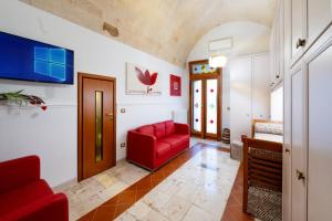 a living room with a red chair and a couch at Il Tulipano Rosso in Oria