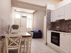 a kitchen with white cabinets and a table and chairs at AL centro in Frattamaggiore