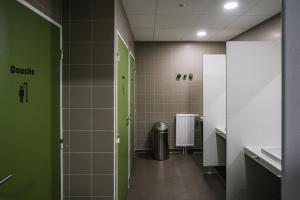 een badkamer met groene en witte tegels en een prullenbak bij Auberge de jeunesse HI Clermont-Ferrand in Clermont-Ferrand