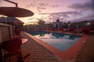 a swimming pool with red chairs and a sunset at Randa Cottages Moshi in Kirua