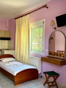 a bedroom with a bed and a mirror and a window at Manolis Studios Thassos in Skala Kallirachis