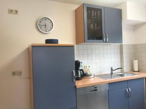 een keuken met een koelkast en een klok aan de muur bij Maxi-Apartment Bodanum - mit eigener Terrasse - naturnahe Ortsrandlage - VDSL - 10 min zum Nürburgring in Bodenbach