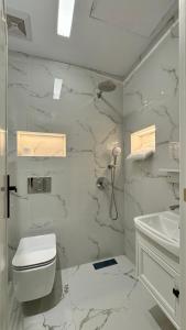 a white bathroom with a toilet and a sink at فندق قمم الصفوه الفندقيه in Rafha