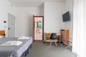 パヴィアにあるUniHo Hostelのベッド2台、デスク、鏡が備わる客室です。