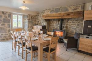 a dining room with a table and chairs and a fireplace at Gites de france 3 epis 8 personnes a malbouzon in Malbouzon