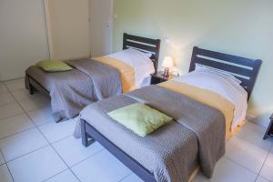 two beds in a room with a couch and a lamp at Gites de france 3 epis 8 personnes a malbouzon in Malbouzon