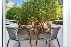 two chairs and a table on a porch with a tree at Stylish Apartment in Glyfada with Outdoor Patio in Athens