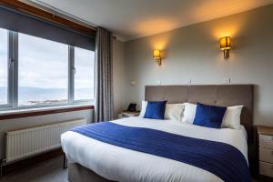 a bedroom with a large bed with blue pillows at Kinloch Hotel, Isle of Arran in Blackwaterfoot