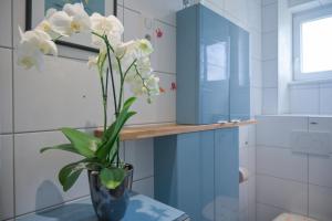 eine Vase mit weißen Blumen auf einem Tisch im Bad in der Unterkunft Colmar Friends and Familly guest home - ALL INCLUSIVE - COLMAR Gare - Jardin - Combles et Vous in Colmar + 78 Fotos