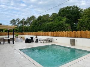 a swimming pool in a patio with a table and chairs at Petit paradis in Soustons