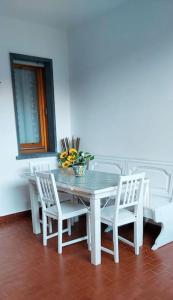 a dining room table with white chairs and a vase of flowers at Casafrancyalmare in Querceta