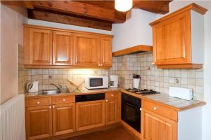a kitchen with wooden cabinets and a sink and a microwave at Gites de france 3 epis 8 personnes a conques les genevriers in La Canourgue
