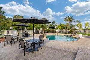 a table and chairs with an umbrella next to a pool at Sleep Inn Clearwater-St Petersburg in Clearwater