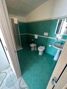 a green bathroom with a toilet and a sink at Hotel Regina del Mare in Ischia
