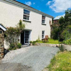 una casa bianca con una panchina in cortile di The Cottage a Exeter