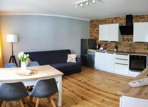a living room with a blue couch and a kitchen at Apartament "Natalia" Pszczew Lubuskie Mazury in Pszczew