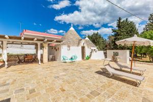a patio with an umbrella and chairs and a house at Trullo DoMi by Perle di Puglia in Noci
