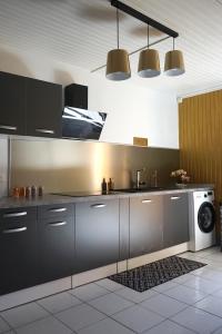 a kitchen with black cabinets and a washing machine at La VOLCANAISE in Village Sainte Anne