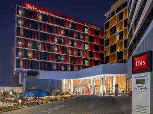 een verlicht gebouw met een bordje voor het gebouw bij ibis Doha in Doha