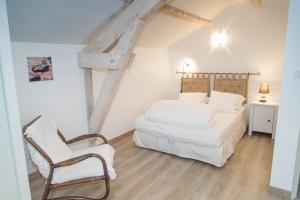 a white bedroom with a bed and a chair at Gîte du haut au cayre in Mas-dʼOrcières