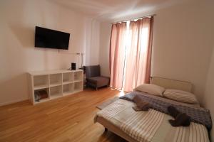 a bedroom with a bed and a television and a chair at Stadtjuwel Apartments 1020 Wien in Vienna