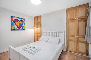 a bedroom with a white bed and a painting on the wall at Pass the Keys Private Garden Apartment by Tulse Hill Station in London