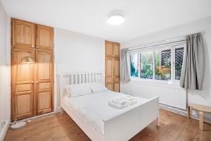 a bedroom with a white bed and a window at Pass the Keys Private Garden Apartment by Tulse Hill Station in London