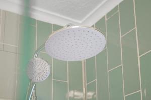 a shower head in a bathroom with blue tiles at Pass the Keys Private Garden Apartment by Tulse Hill Station in London
